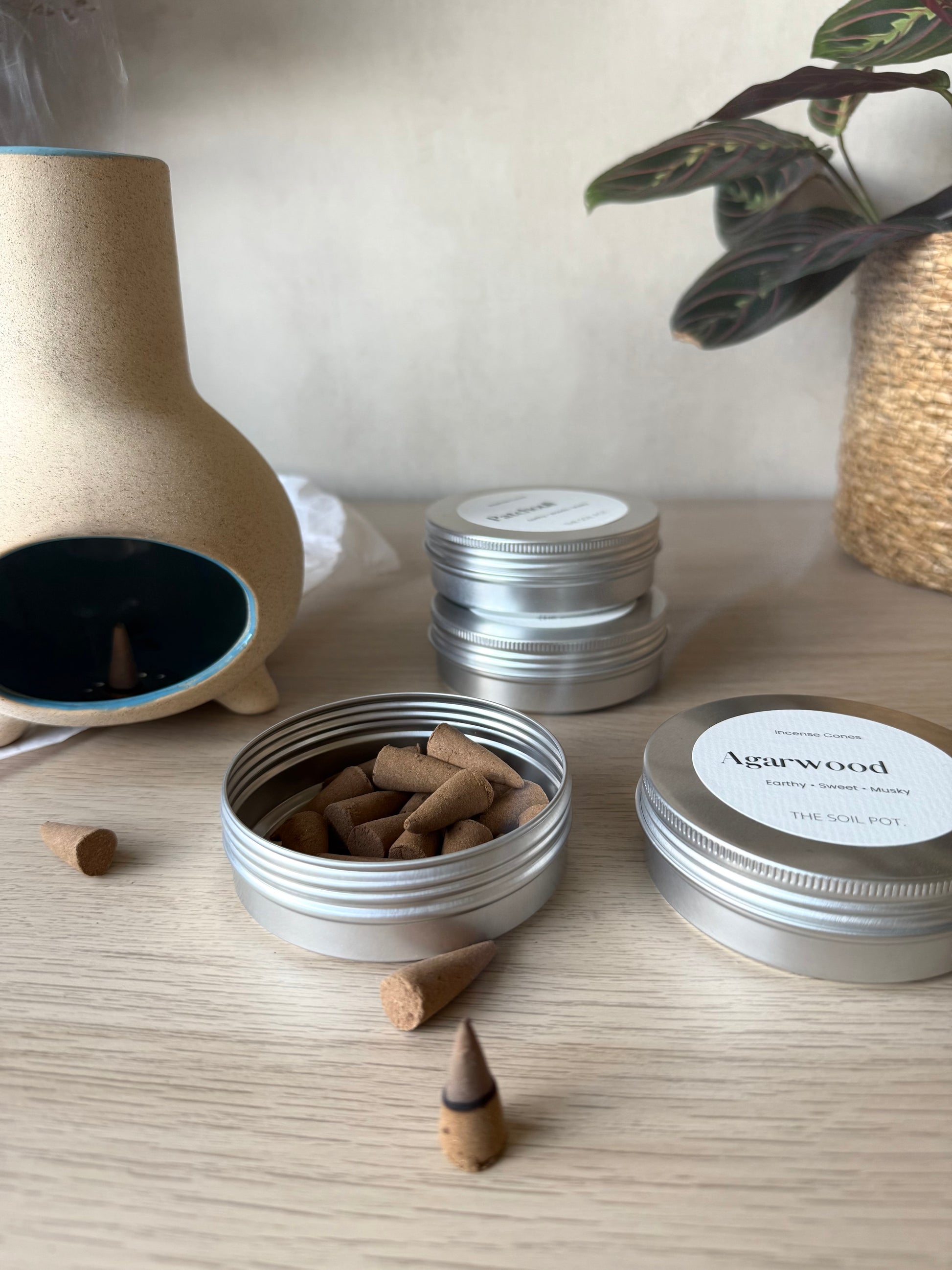 Incense cones in a metal container with other incense products on a wooden surface.