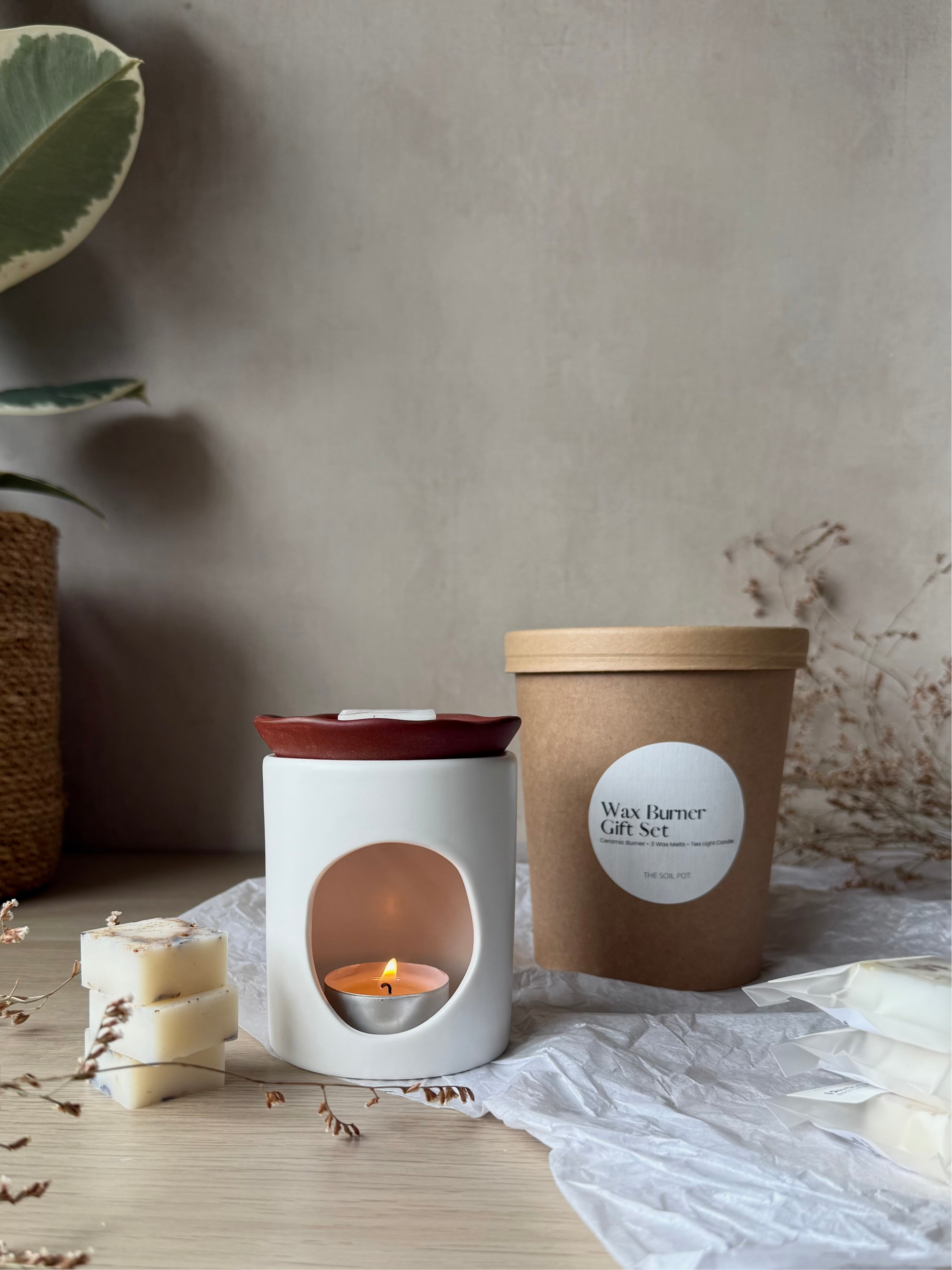 Wax burner gift set with a candle and packaging on a neutral background